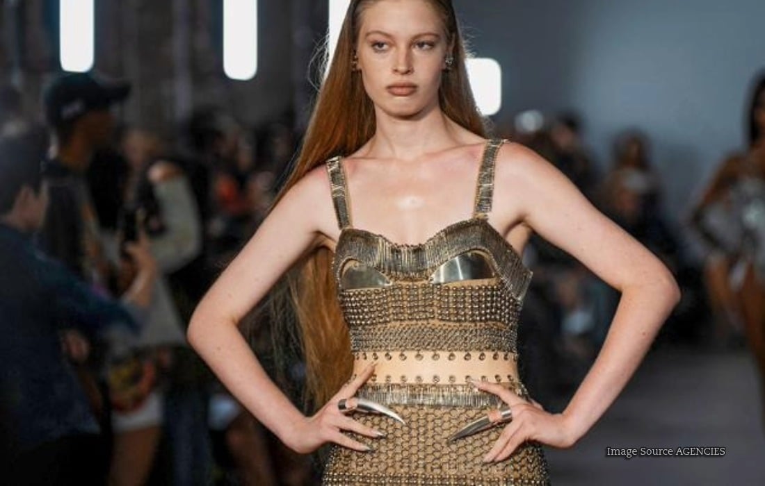 Vivian Jenna Wilson poses alongside malfunctioning humanoid robot DESI84 in Desigual's anti-AI fashion campaign.