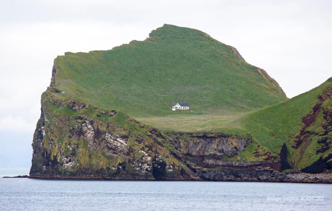 Iceland’s loneliest house on green Elliðaey Island, surrounded by steep cliffs and the North Atlantic Ocean.