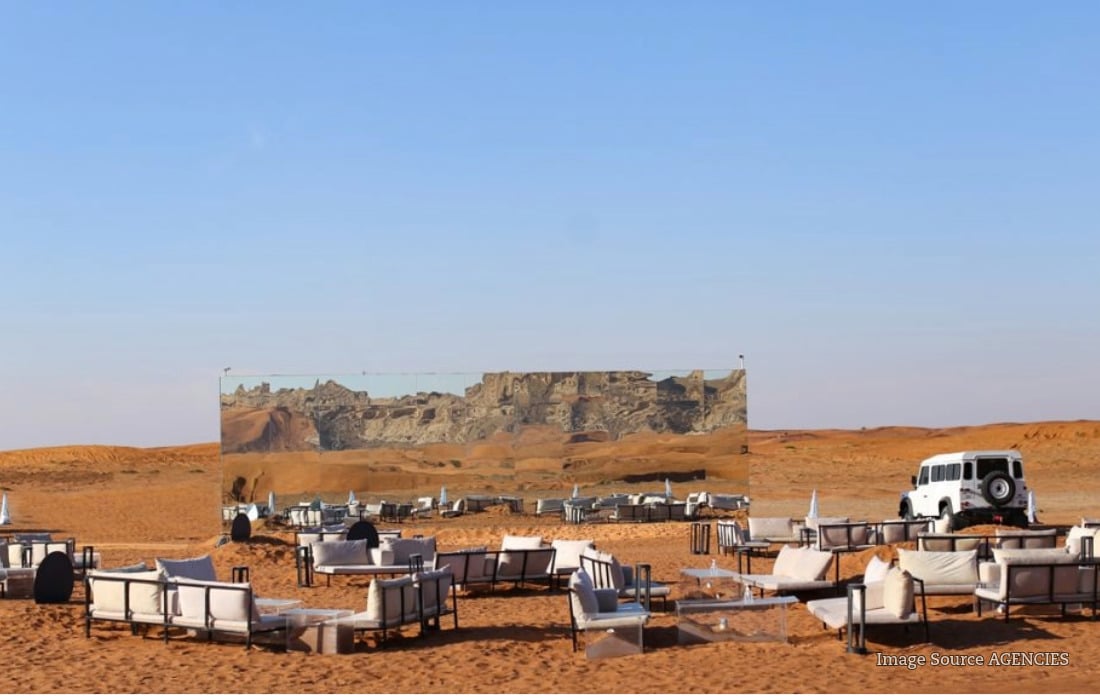 Outdoor seating at a UAE desert café with warm lights, coffee tables and sand dunes at sunset.
