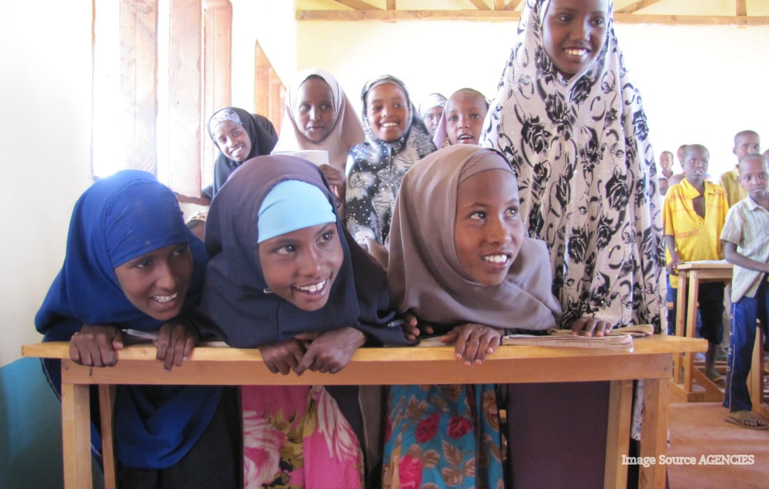 Refugee children studying in a classroom as funding cuts threaten access to education.