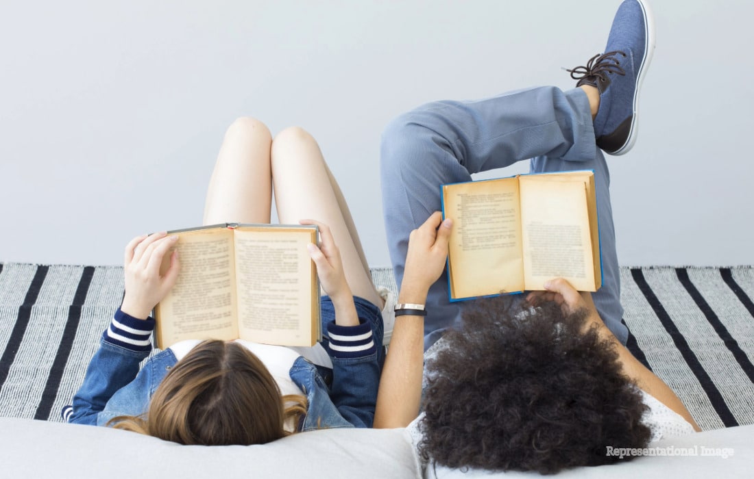 Young Gen Z readers using smartphones alongside books as a TikTok debate raises questions about changing reading habits.